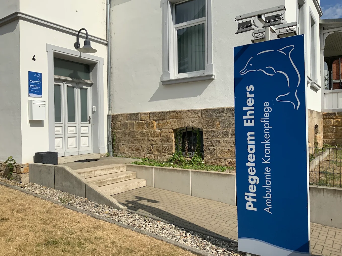 Der Eingang unseres Hauses in Bad Salzdetfurth: Treppe und Haustür mit dem blauen Praxisschild des Pflegeteams Ehlers